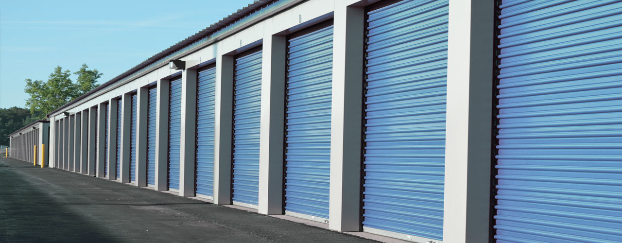 Row of blue roll-up drive-up storage units at Budget Self Storage